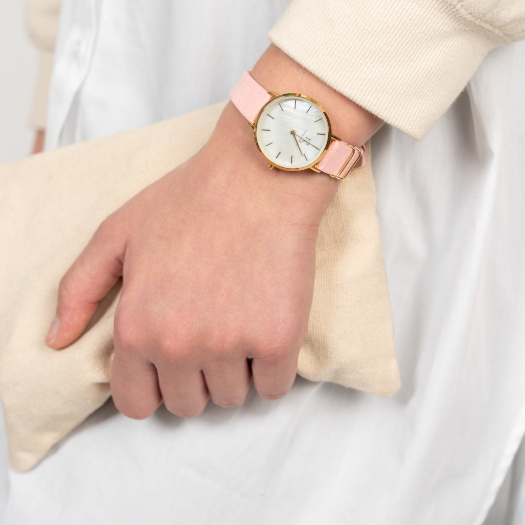 Frau trägt die Victor De Rossa Armbanduhr „Sedurre 868“ mit rosa Wildlederarmband, Perlmutt Zifferblatt und goldenem Gehäuse