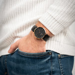 Mann trägt die Victor De Rossa Armbanduhr „Aperto 301“ mit schwarzem Lederarmband schwarzem Zifferblatt und rosegoldenem Gehäuse