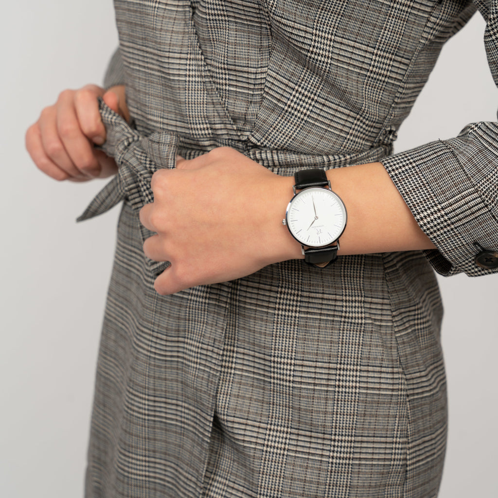 Frau trägt die Victor De Rossa Armbanduhr „Aperto 501“ mit schwarzem Lederarmband, weißem Zifferblatt und silbernem Gehäuse