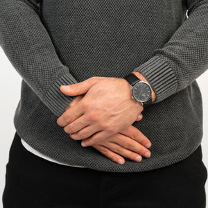 Mann trägt die Victor De Rossa Armbanduhr „Aperto 551“ mit schwarzem Lederarmband, schwarzem Zifferblatt und silbernem Gehäuse